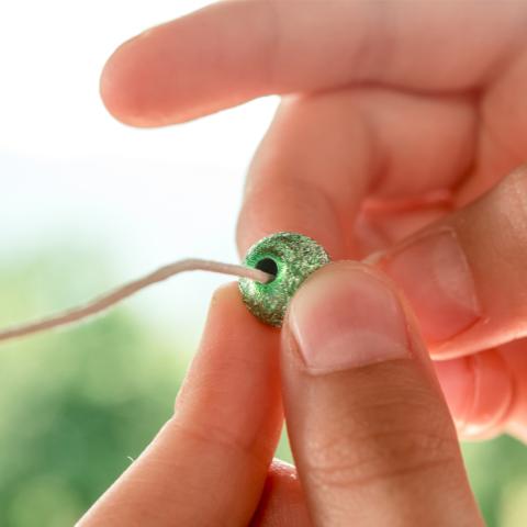 Hand putting bead on a string