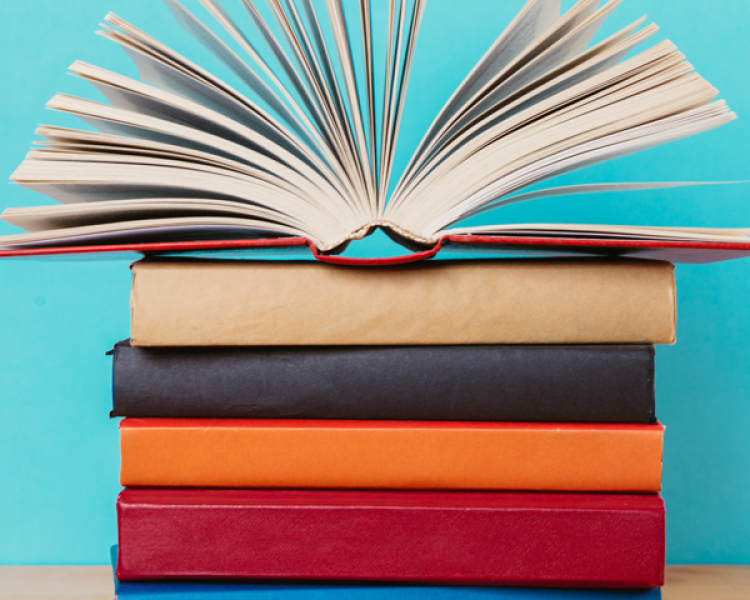 Colorful book stack on a blue background with an open book on top